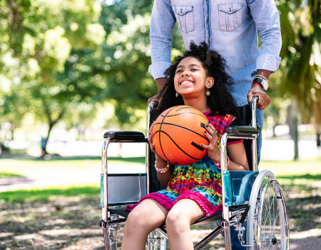 Girl in a wheelchair holding a basketball